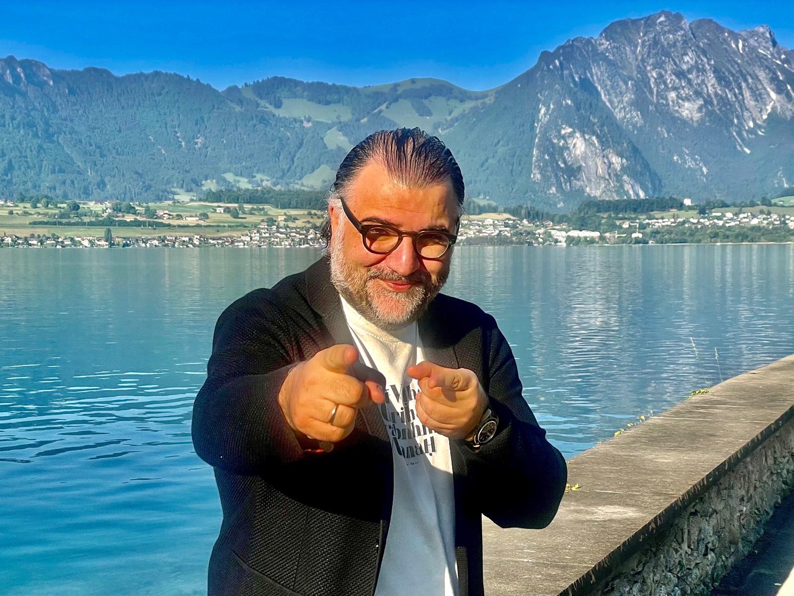 Georgios Balatsinos by Lake Thun, with the Swiss Alps behind him