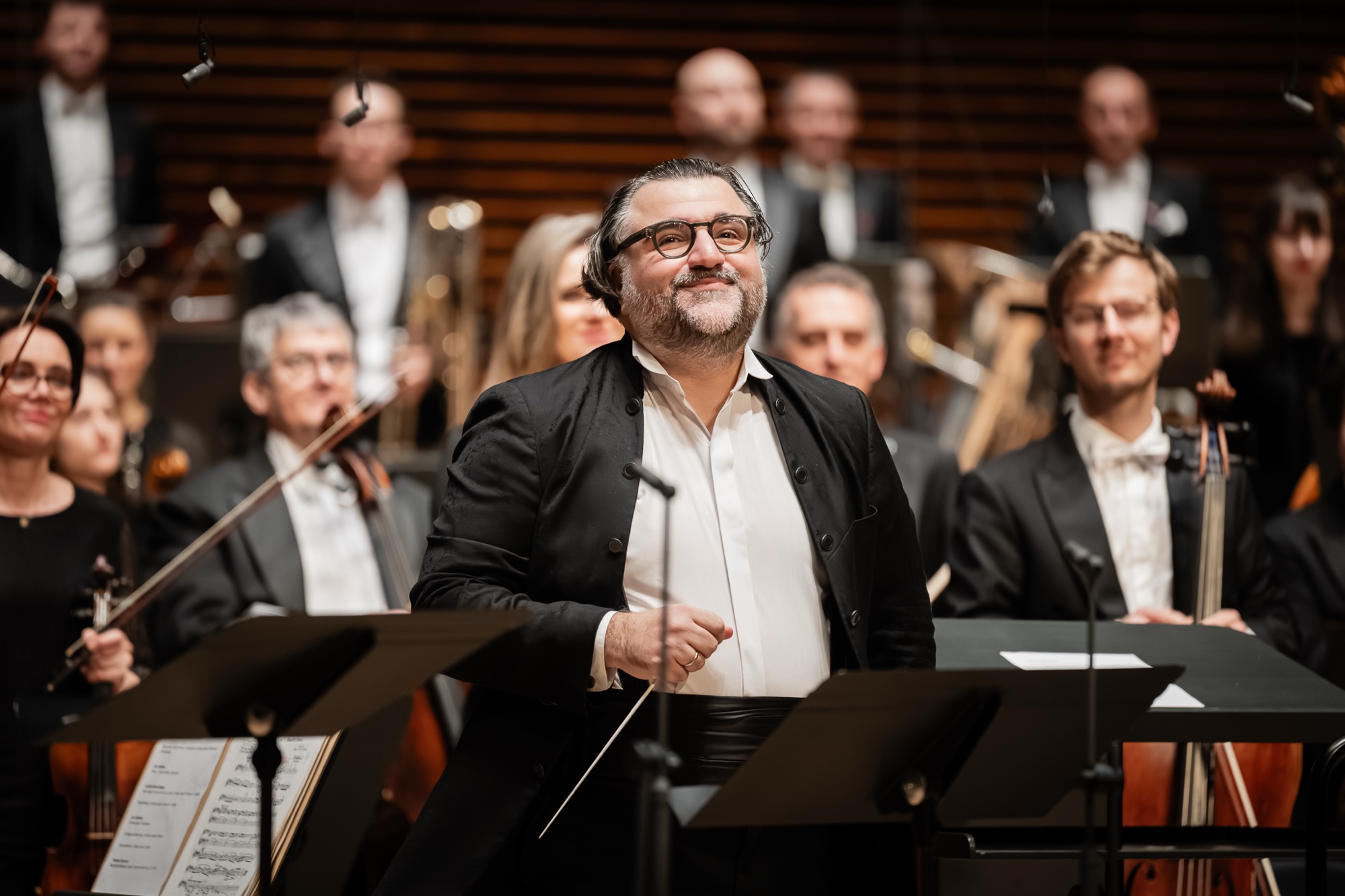 Georgios Balatsinos smiling on the podium with the orchestra
